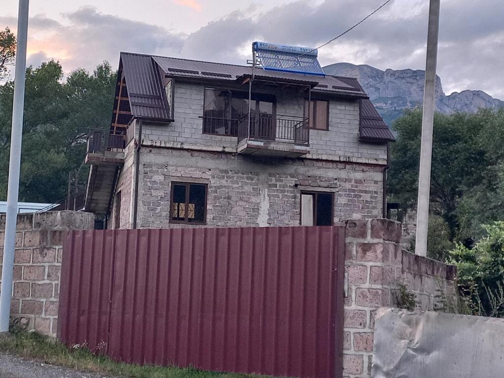 una vecchia casa di mattoni con una recinzione rossa di Частный дом Агарцин a Haghartsin