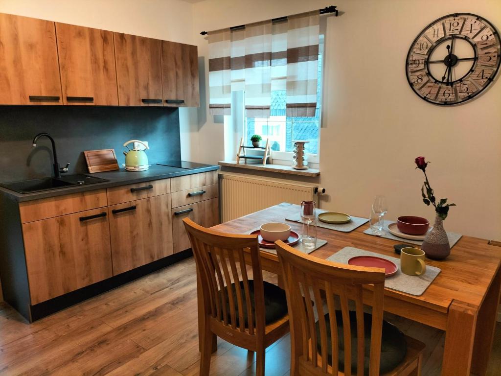 a kitchen with a wooden table and a clock on the wall at Ferienwohnung Emilie in Masserberg
