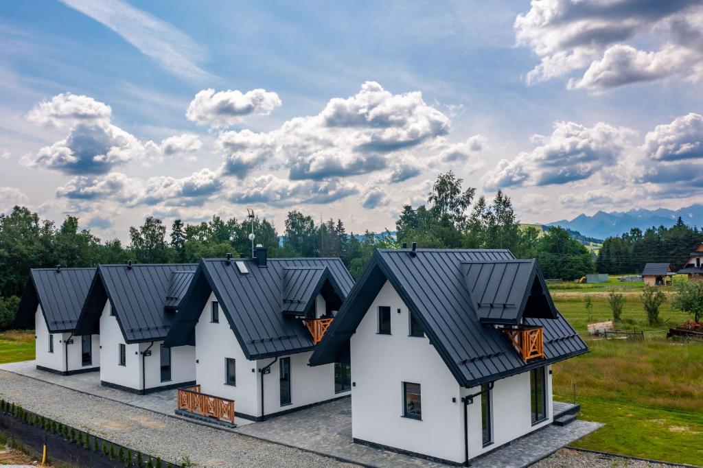 eine Reihe von weißen Häusern mit schwarzen Dächern in der Unterkunft Folk Vibe in Białka Tatrzańska