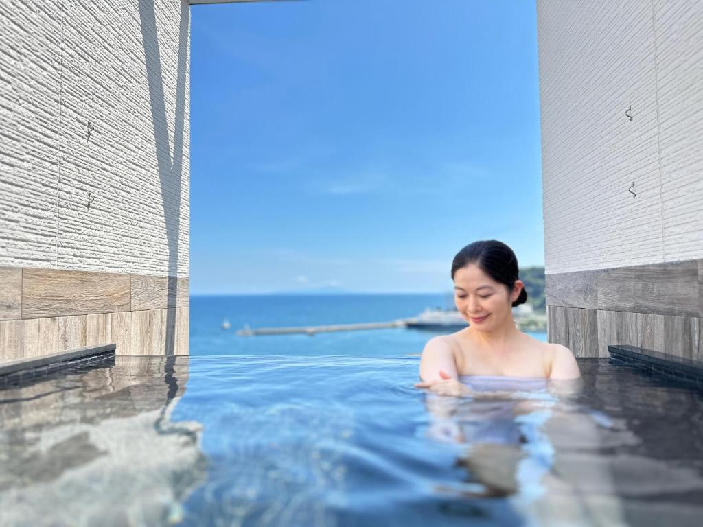 een vrouw zit in een bubbelbad bij Grandview Atami Private Hot Spring Condominium Hotel in Atami