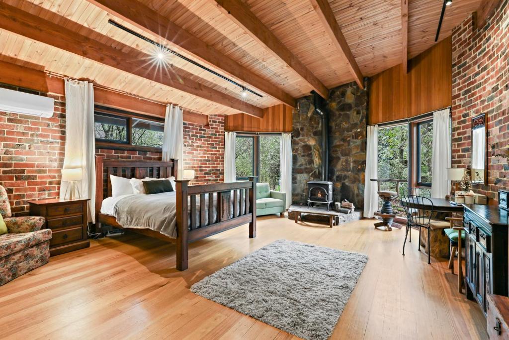 um quarto com uma cama e uma parede de tijolos em Birch Suite - Rocky Creek Art Garden em Olinda