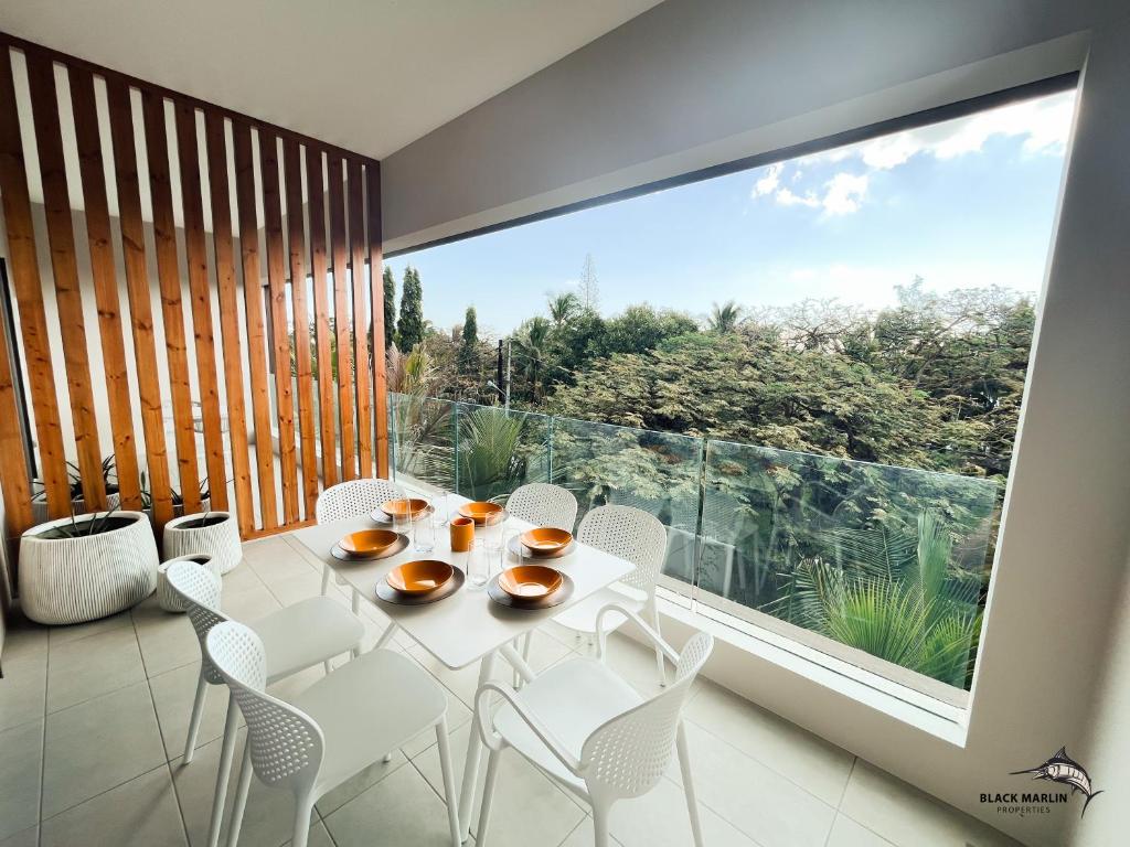 einen weißen Tisch und Stühle in einem Zimmer mit einem großen Fenster in der Unterkunft Black Marlin Apartments in Pereybere