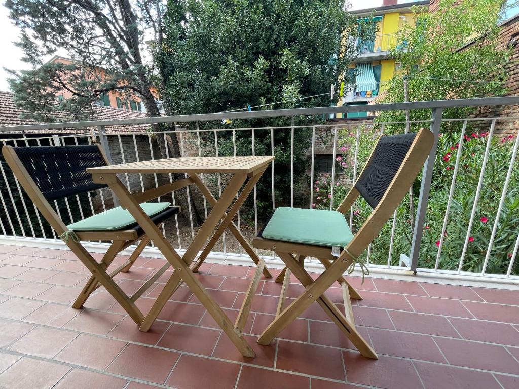 un tavolo in legno e 2 sedie sul balcone di Romagna Apartments a Massa Lombarda