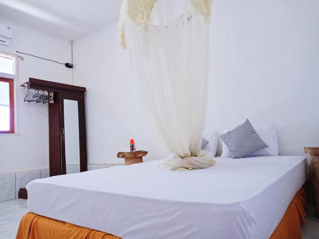 1 dormitorio con 1 cama blanca grande con cortinas en Rocky homestay lakey nangas beach en Huu