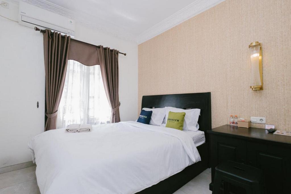 a bedroom with a large white bed and a window at Urbanview Hotel Sultan Palace Malang by RedDoorz in Dau