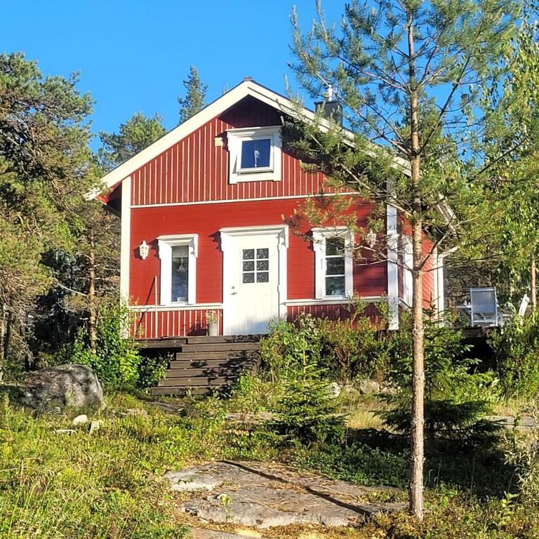 uma casa vermelha com uma árvore em frente em Stuga em Sävar