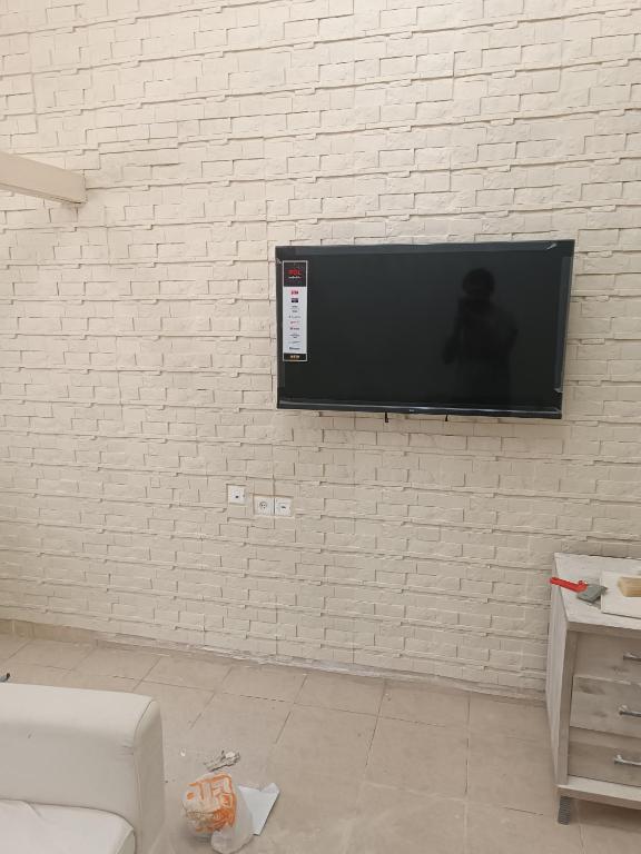 TV de pantalla plana colgada en una pared de ladrillo blanco en דירת נופש en Haifa