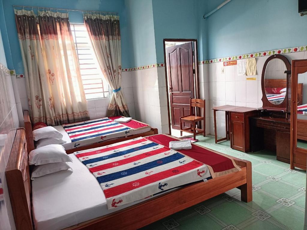 a bedroom with two beds and a desk and a mirror at Khách sạn Ngọc Mai 2 in Can Tho