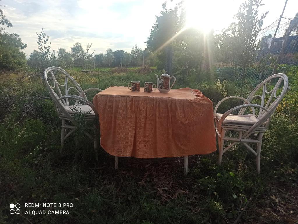 a table and two chairs with a table and the sun at The Endless Enigma in Tazroutane