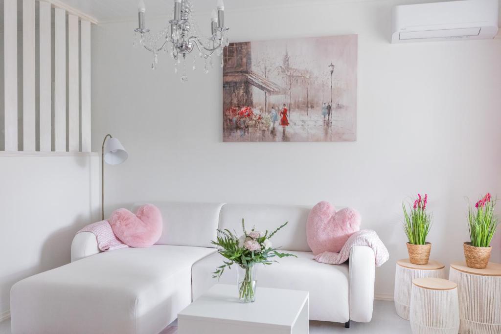 a living room with a white couch and pink chairs at City Holiday Apartments 2 in Rovaniemi