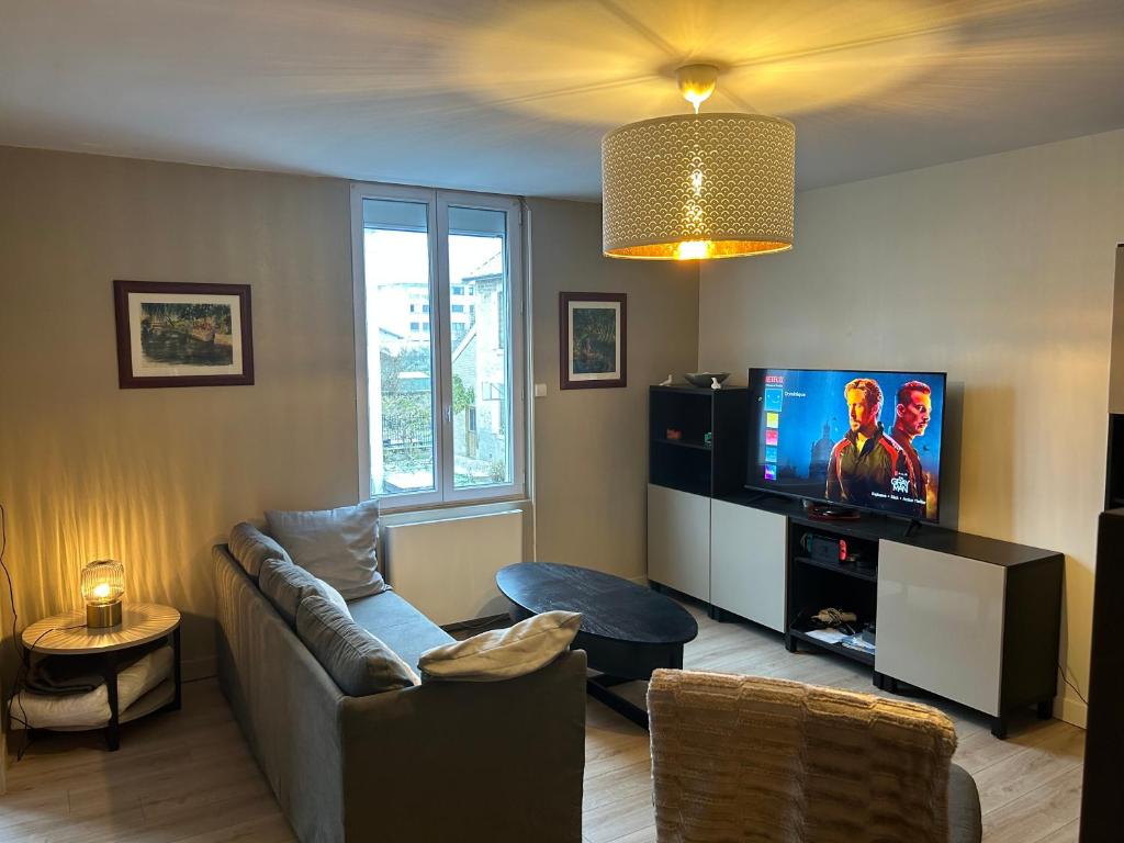 salon z kanapą i telewizorem z płaskim ekranem w obiekcie Grand appartement de standing w mieście Saint-Dizier