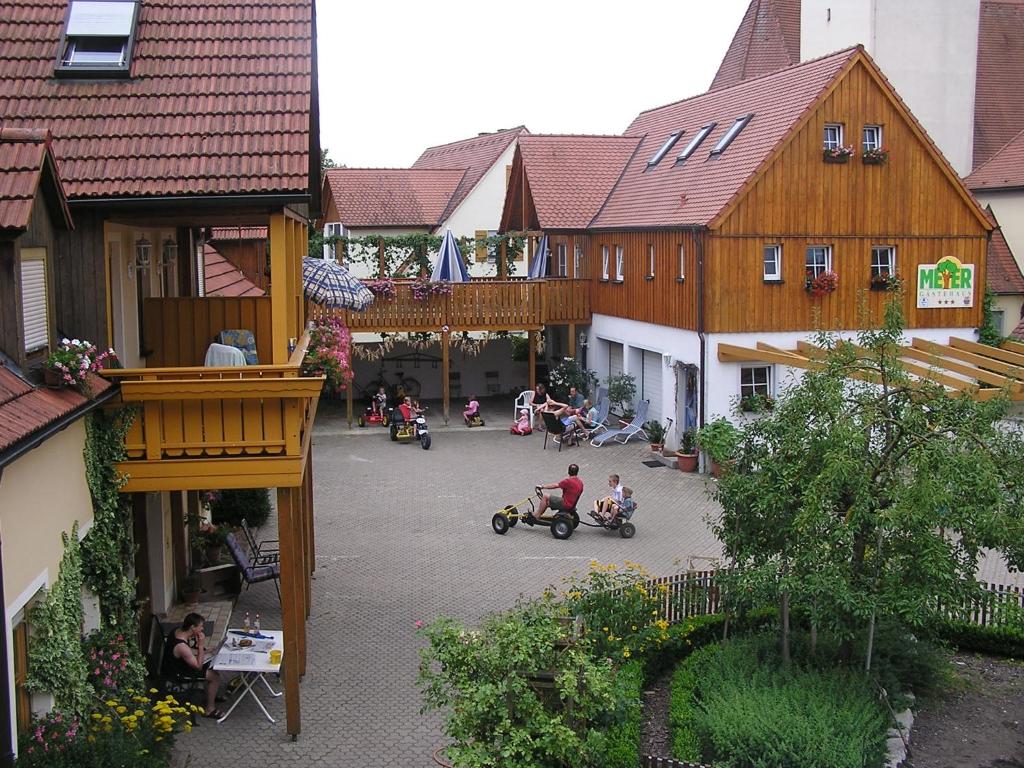 Ferienhaus Meyer في غونزنهاوزن: مجموعة من الأشخاص يركبون السكوتر في ساحة ذات مباني خشبية