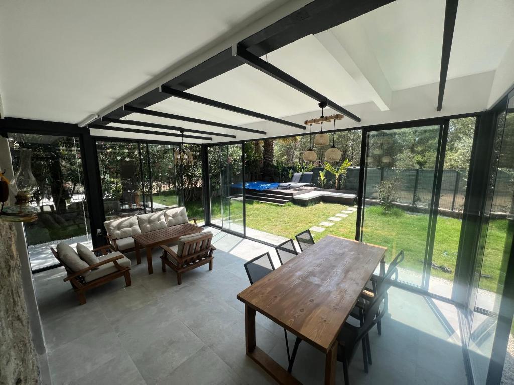 eine abgeschirmte Terrasse mit einem Holztisch und Stühlen in der Unterkunft Oludeniz Luxury Villa with Jacuzzi, Common Pool in Fethiye