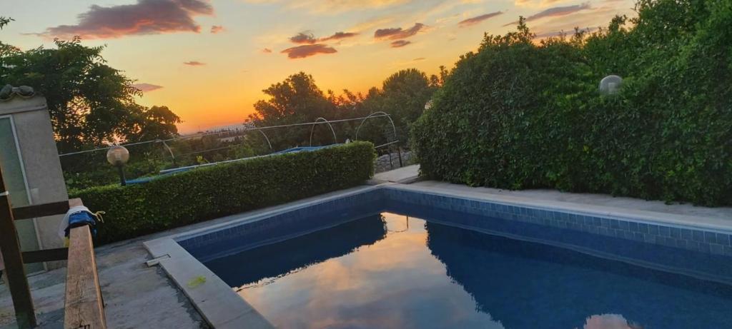 a swimming pool with a sunset in the background at Vento Del Sud in Chiaramonte Gulfi