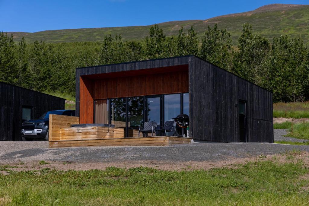 a black house with a deck with a car parked in it at North Mountain View Suites in Akureyri