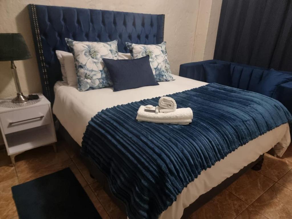 a bed with a blue blanket and a towel on it at Monate BNB in Kuruman