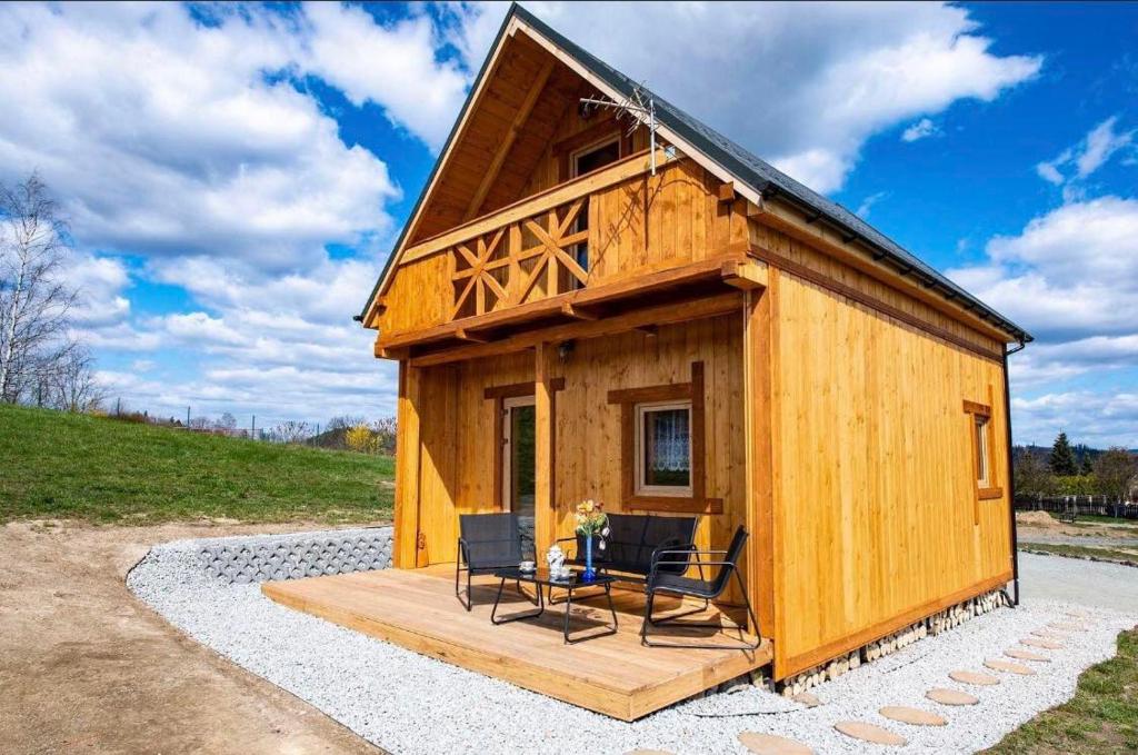 a small wooden cabin with a deck and chairs at Rajskie wzgórze w Karkonoszach in Łomnica