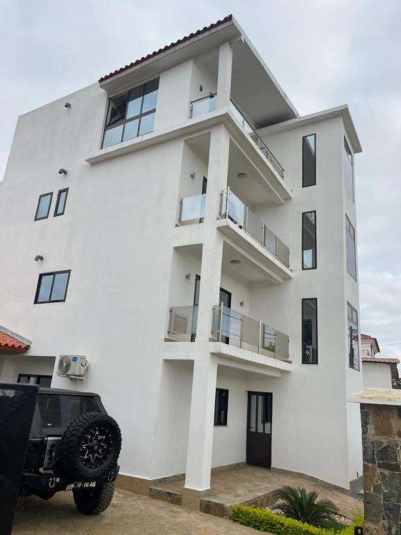 ein weißes Haus mit einem davor geparkt in der Unterkunft Hotel Kenito Apartamentos T1 To T3 in São Tomé