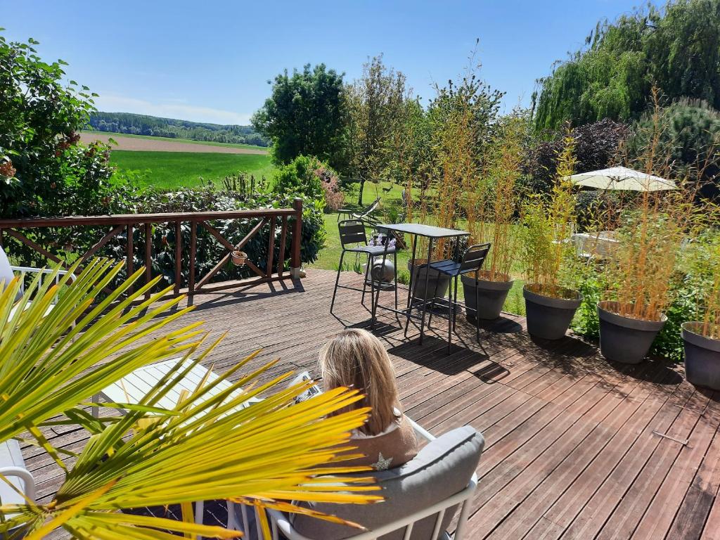 une femme est assise sur une terrasse en bois dans l'établissement La Grange, à Savonnières