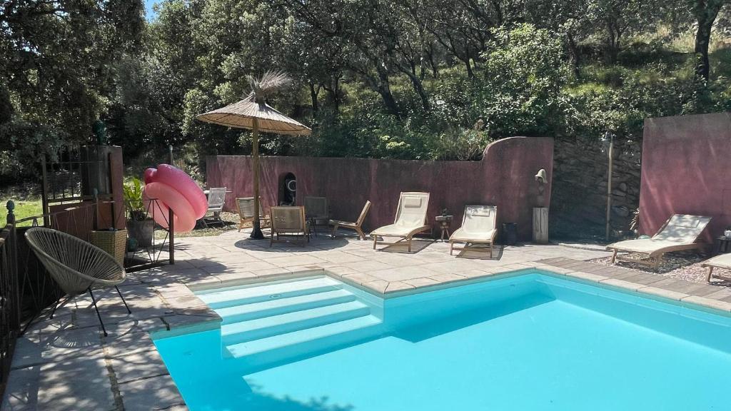 - une piscine bleue avec des chaises et un parasol dans l'établissement Jolie annexe du mas dans le cœur de la garrigue nîmoise, à Nîmes