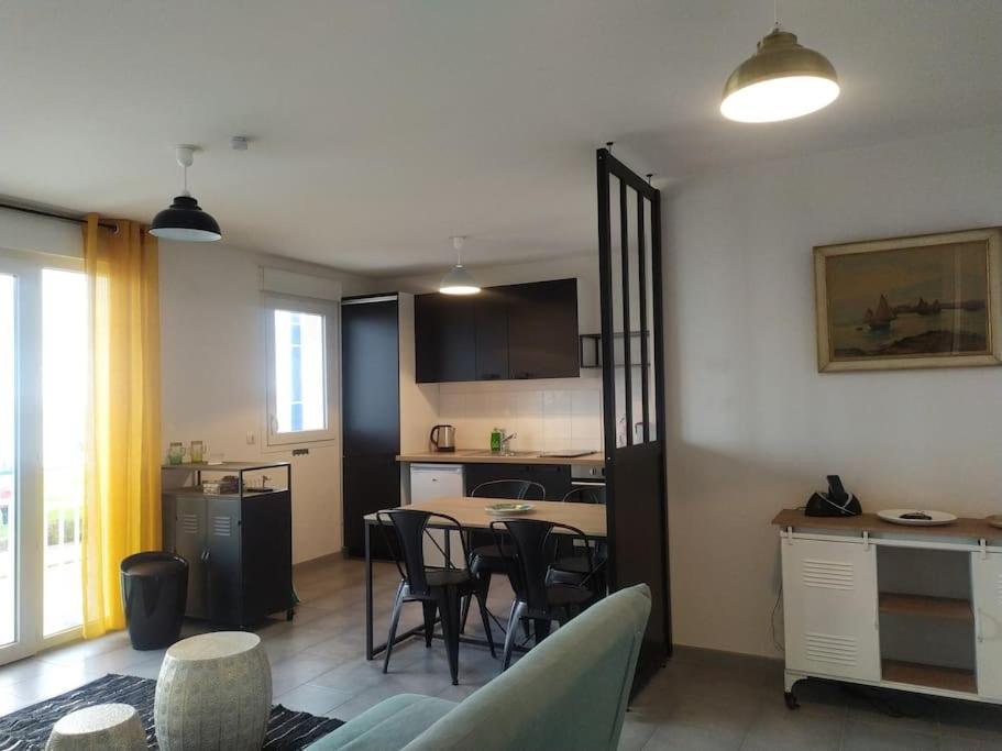 een woonkamer met een keuken en een tafel en stoelen bij Très bel F2 avec pleine vue mer. in Langrune-sur-Mer