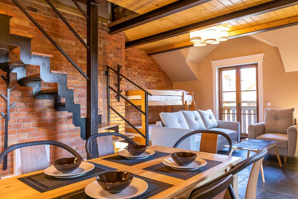 a room with a table and chairs and a brick wall at RentPlanet - Apartament Waryńskiego in Szklarska Poręba