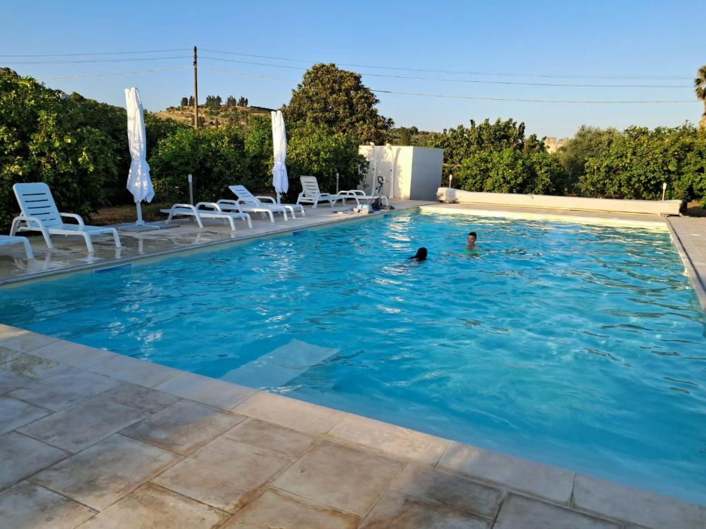 a swimming pool with two people in the water at L'antico Trappeto Holiday Home in Noto