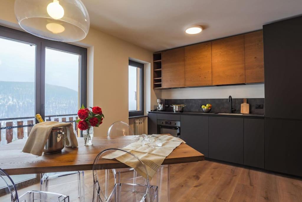 een keuken met een tafel met stoelen en een groot raam bij La Rosa delle Alpi Luxury Apartment in Chamois