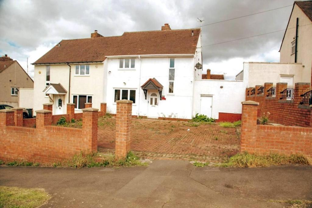 a white house behind a brick fence at Immaculate 3-Bed House in Dudley in Dudley