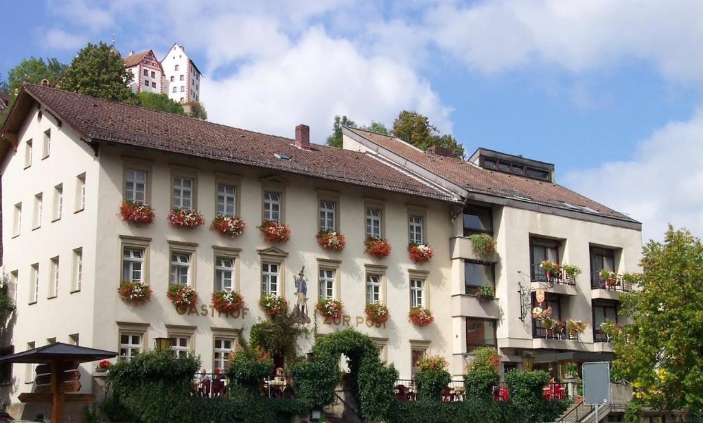 ein großes weißes Gebäude mit Blumen an den Fenstern in der Unterkunft Gasthof Hotel zur Post in Egloffstein