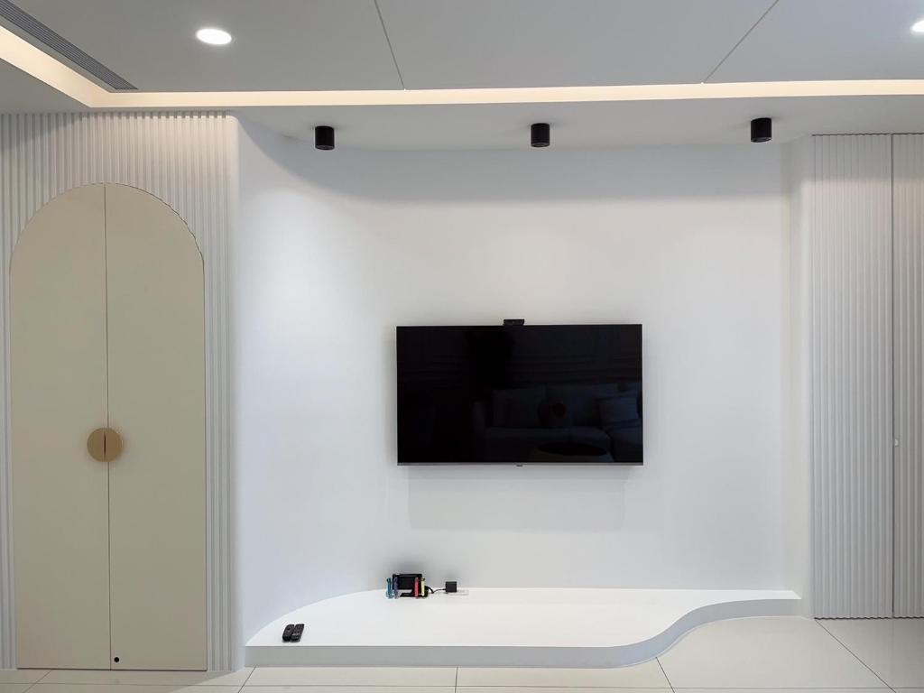 een witte kamer met een tv aan de muur bij Muzhu B&B in Yilan