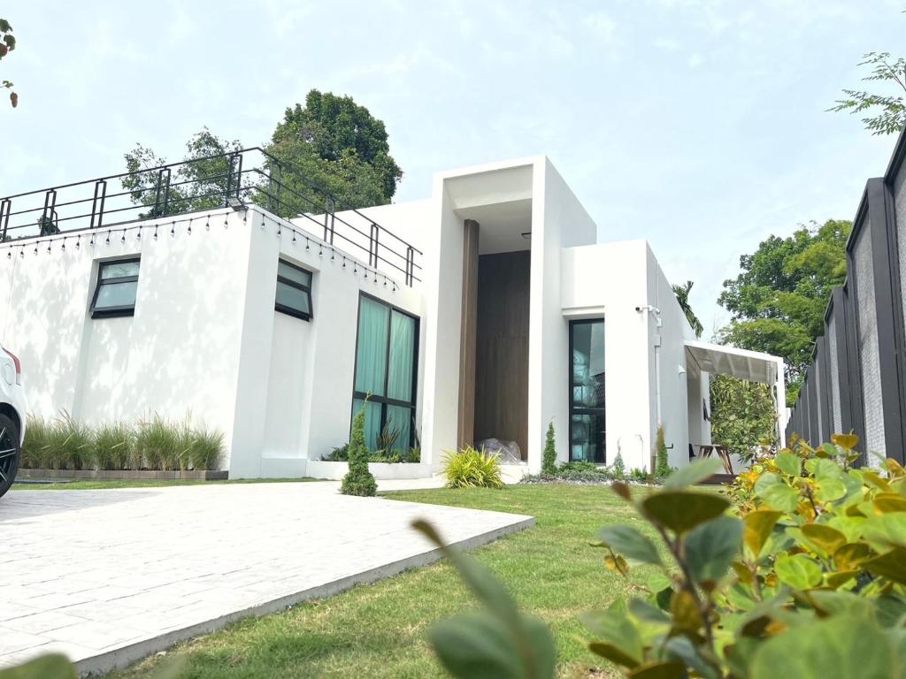 a white house with a courtyard at 168 Garden Pool Villa in Nong Prue