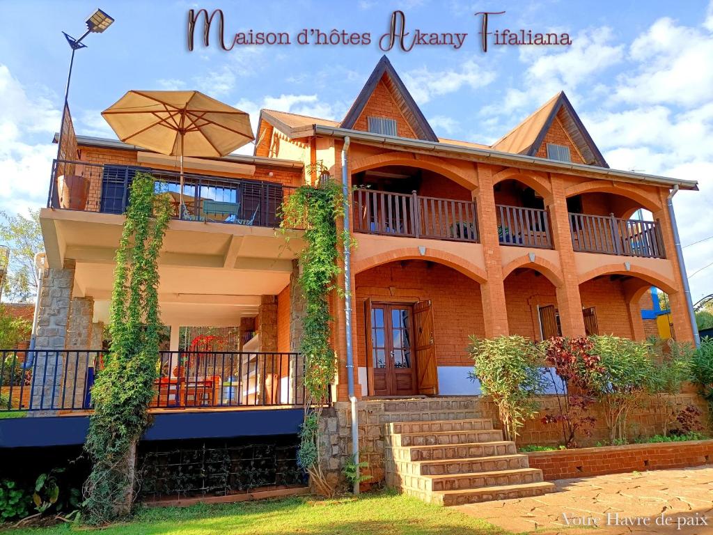 a large house with a balcony and an umbrella at Maison d'hôtes Akany Fifaliana in Antananarivo