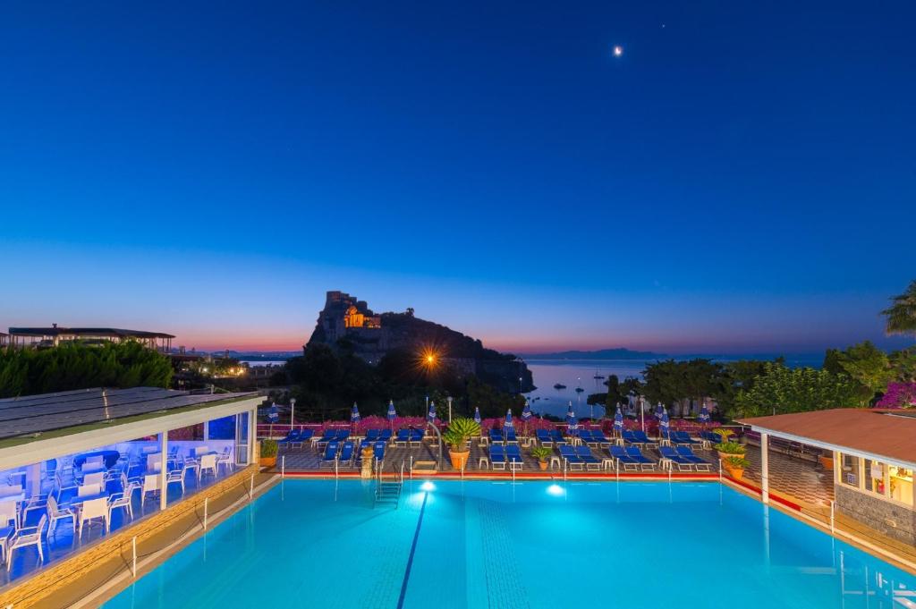 una piscina notturna con vista su un castello di Hotel Parco Cartaromana a Ischia