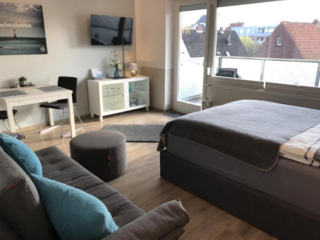 a bedroom with a bed and a desk and a couch at Ferienwohnung Hallix - Wilhelmshaven in Wilhelmshaven