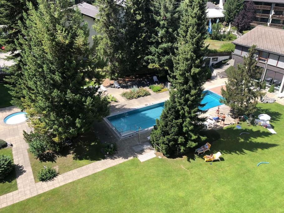 een uitzicht over een zwembad in een tuin met bomen bij Laax with indoor and outside pool, sauna, 200 Meter to Ski lift , Fitnessroom, Tennis Place, Joyroom, Parkstadion Reserve in Laax