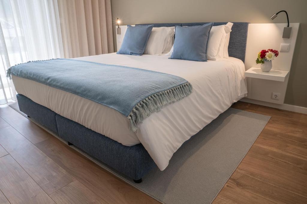 1 dormitorio con 1 cama grande con almohadas azules y blancas en Geonature, en Macedo de Cavaleiros