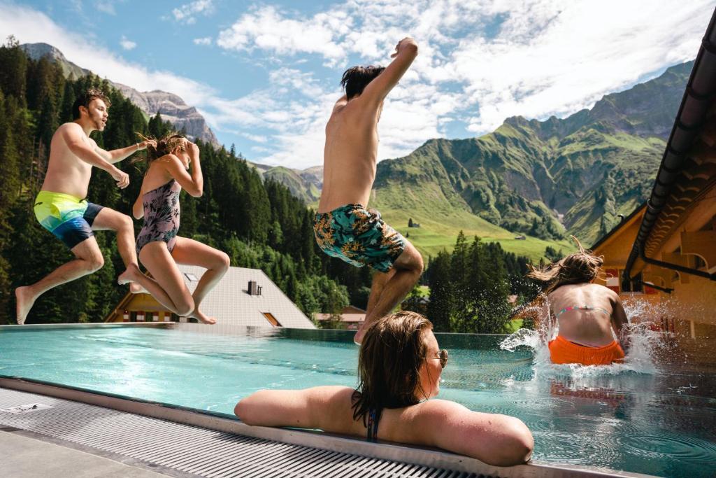 a group of people jumping into a swimming pool at Berghaus Schröcken - Hotel Apartments Spa in Schröcken