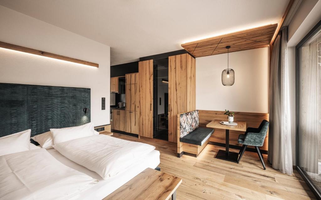 Wagnerhof Apartments في بيرتيساو: غرفة نوم بسرير وطاولة وكرسي