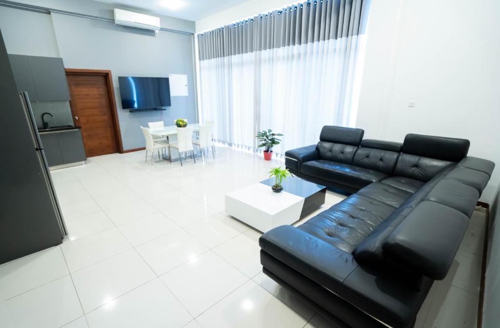 - un salon avec un canapé en cuir noir et une table dans l'établissement Quest Colombo Residencies, à Talawatugoda