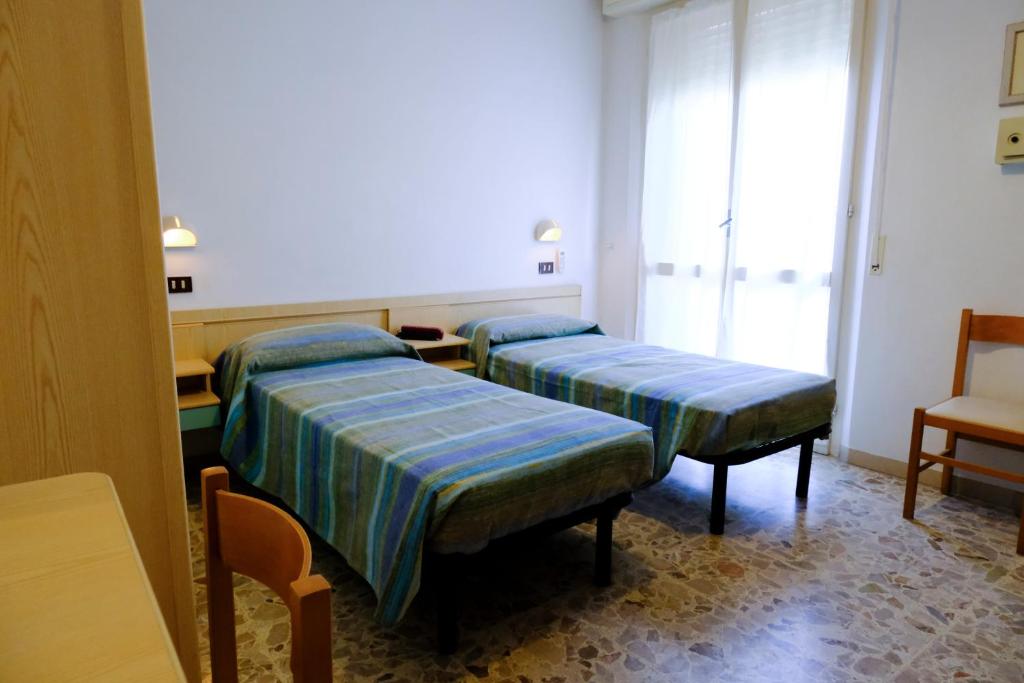 a hospital room with two beds and a chair at Hotel Chiara in Rimini