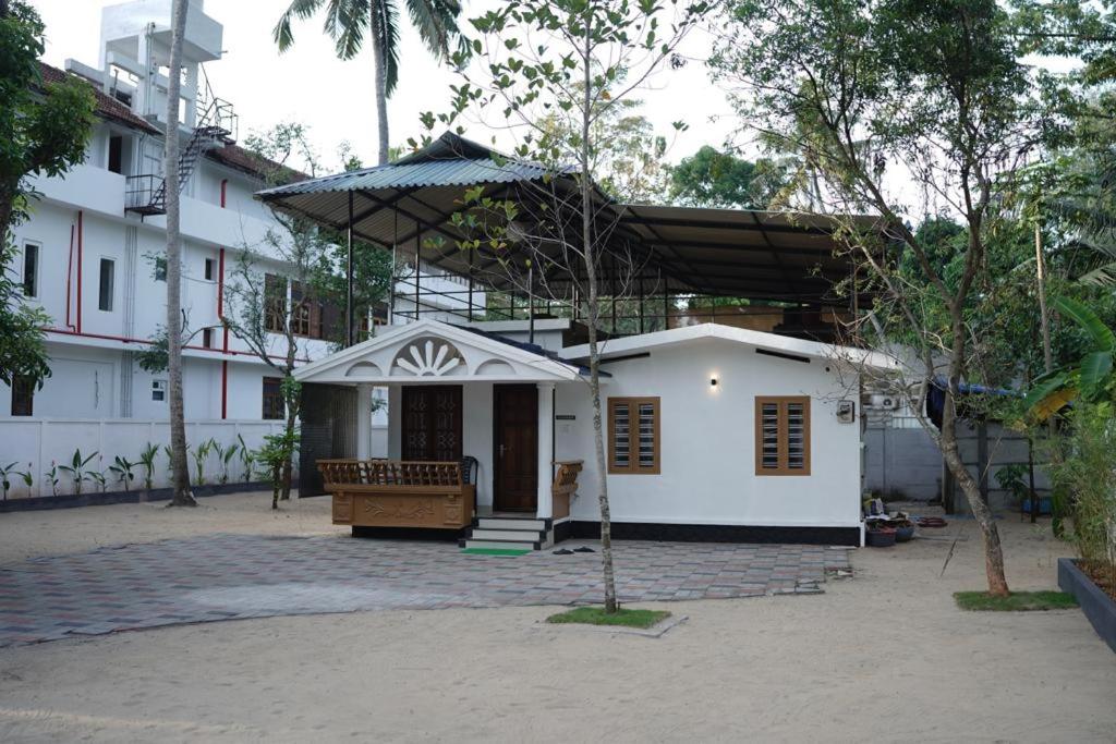 Pallipuram的住宿－EDEN BEACH VILLA，一座带门廊和遮阳伞的白色小房子