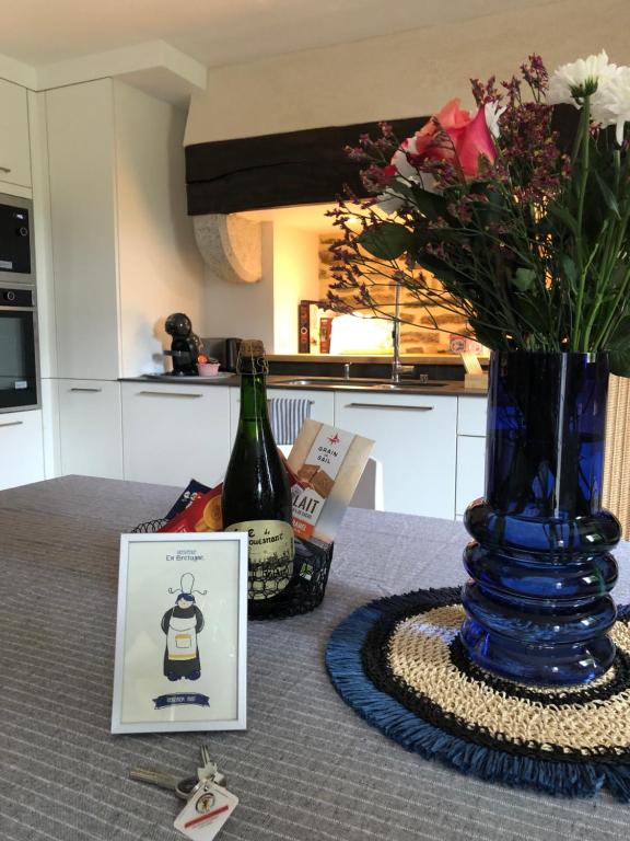 a table with a bottle of wine and a vase with flowers at Le Penty du Petit-Kerauret in Concarneau
