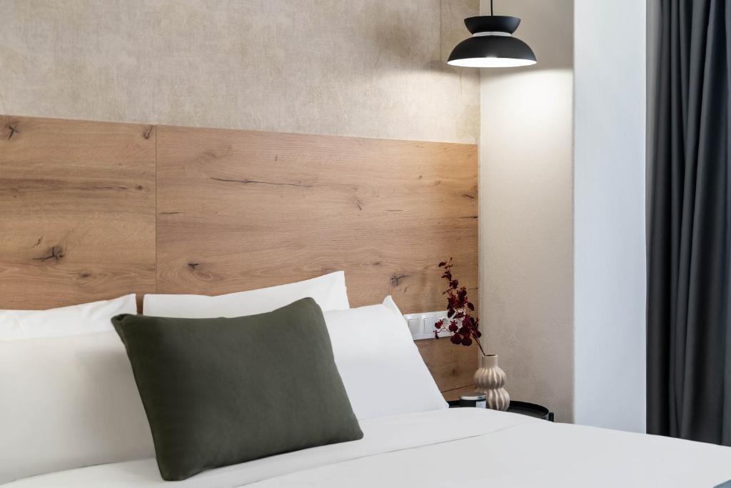 a bedroom with a white bed with a wooden headboard at KOYO Athens in Athens