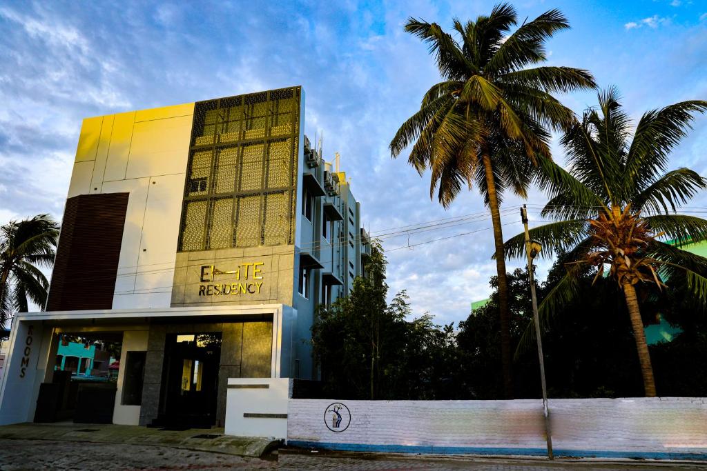a building with palm trees in front of it at ELITE RESIDENCY in Palni