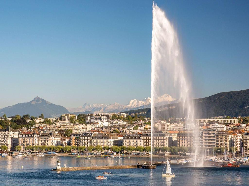 a fountain in the water in front of a city at Fairmont Grand Hotel Geneva in Geneva