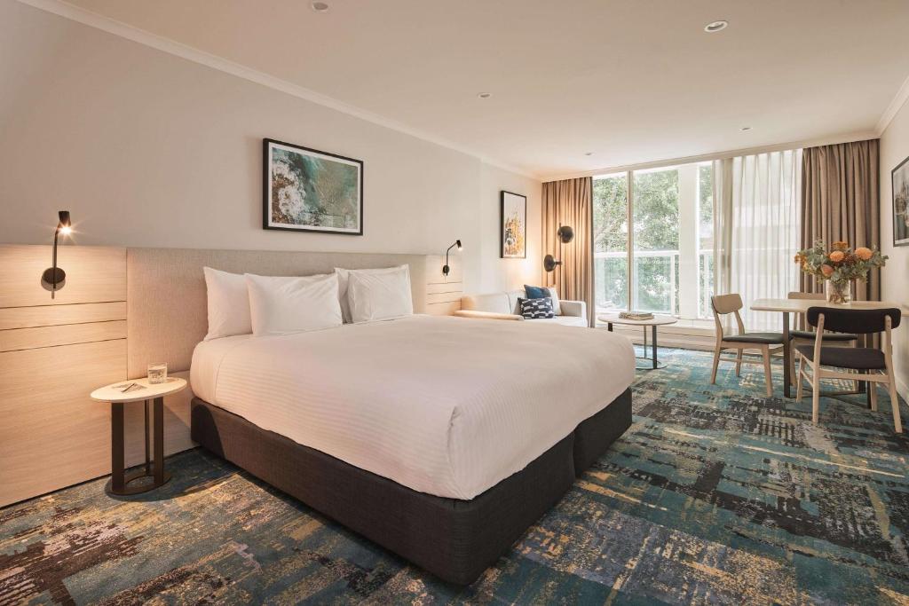 a hotel room with a large bed and a table at Rydges Darling Square Apartment Hotel in Sydney