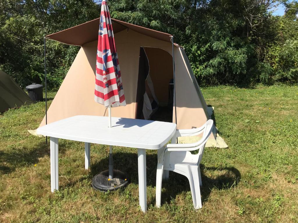 a tent and a white table with an umbrella at Tente Nature 2 personnes in Saint-Sever