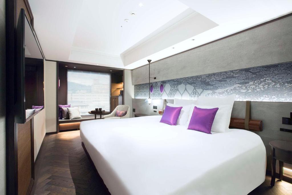 a bedroom with a large white bed with purple pillows at Dhawa Yura Kyoto - Banyan Group in Kyoto