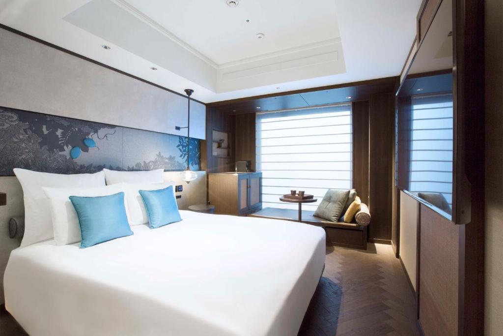 a bedroom with a large white bed with blue pillows at Dhawa Yura Kyoto - Banyan Group in Kyoto